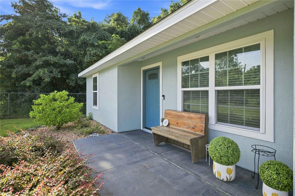A light blue house exterior features a front porch with a wooden bench and plants — 1864 NE 126TH LANE, ANTHONY, FL