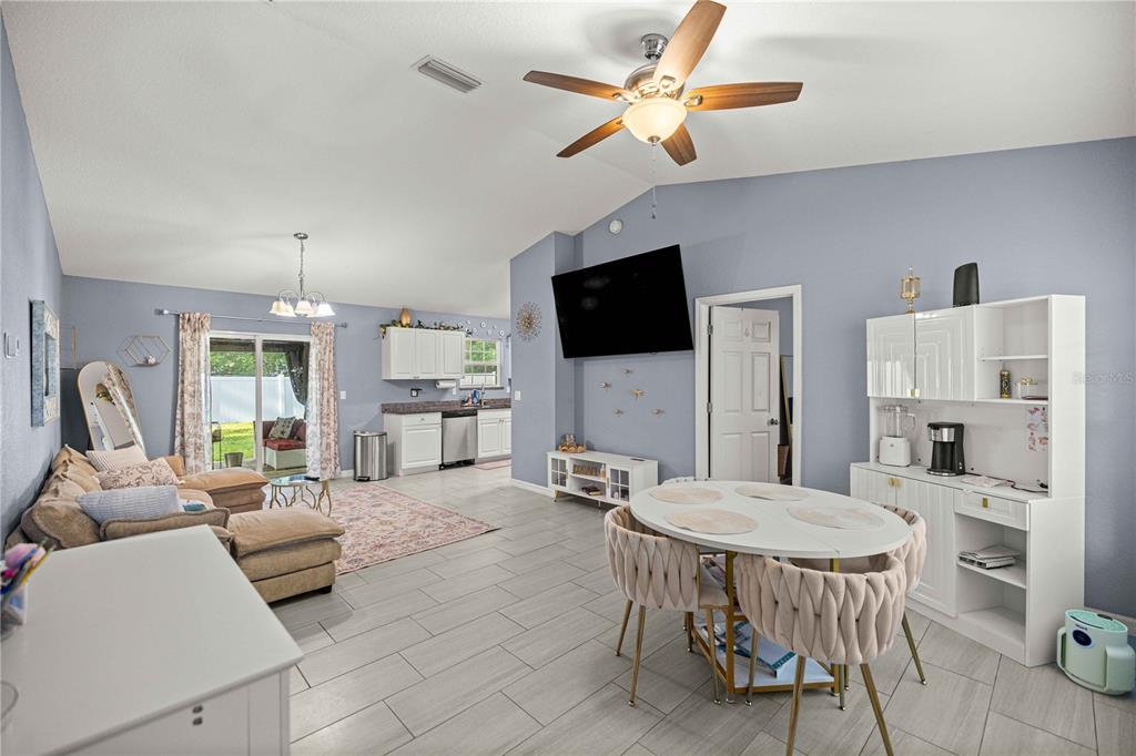 An open-concept living and dining area features light blue walls, tile flooring, and a ceiling fan — 1864 NE 126TH LANE, ANTHONY, FL