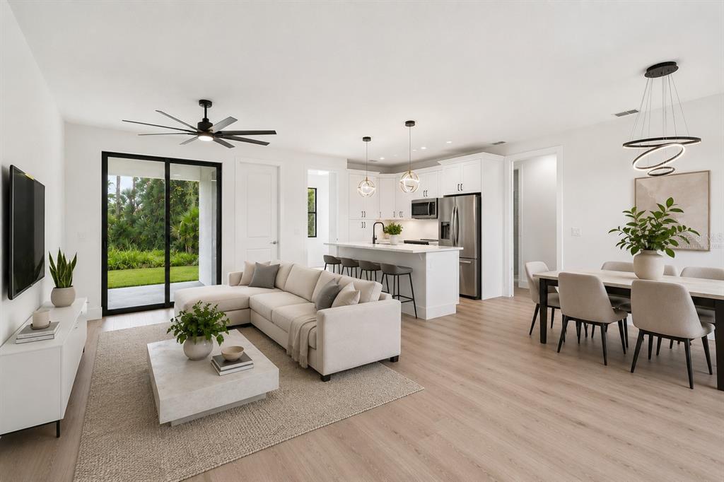 A bright open-concept living and dining area with white cabinetry, light wood floors, and furniture — 17156 EUGENE AVENUE, PORT CHARLOTTE, FL