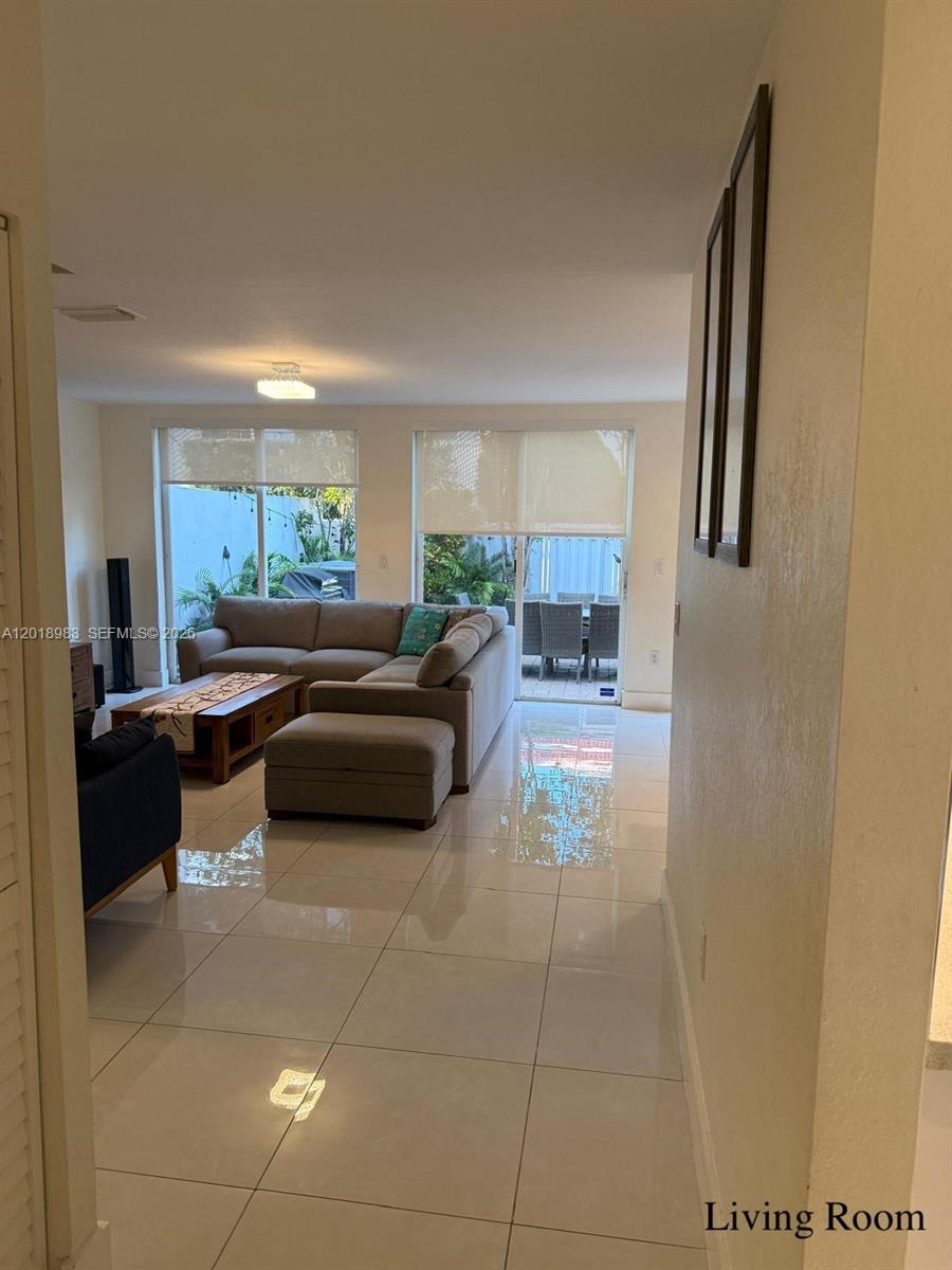 A living room with light tile floors, a sectional sofa, and sliding glass doors — 10973 NW 62nd Ter, Doral FL 33178, DORAL, FL