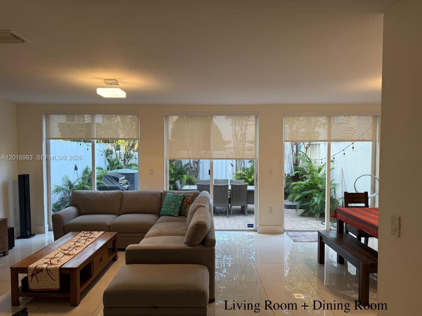 A living and dining room with tile floors, a sectional sofa, and sliding glass doors — 10973 NW 62nd Ter, Doral FL 33178, DORAL, FL