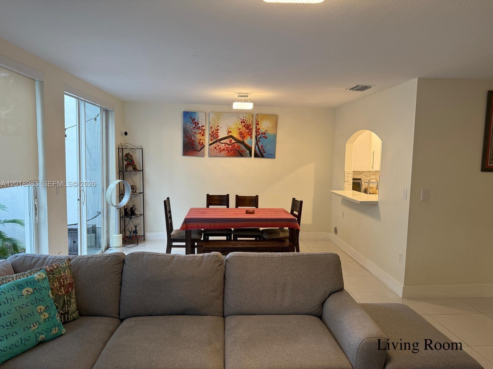 A dining area with a table and chairs sits adjacent to a kitchen pass-through window — 10973 NW 62nd Ter, Doral FL 33178, DORAL, FL