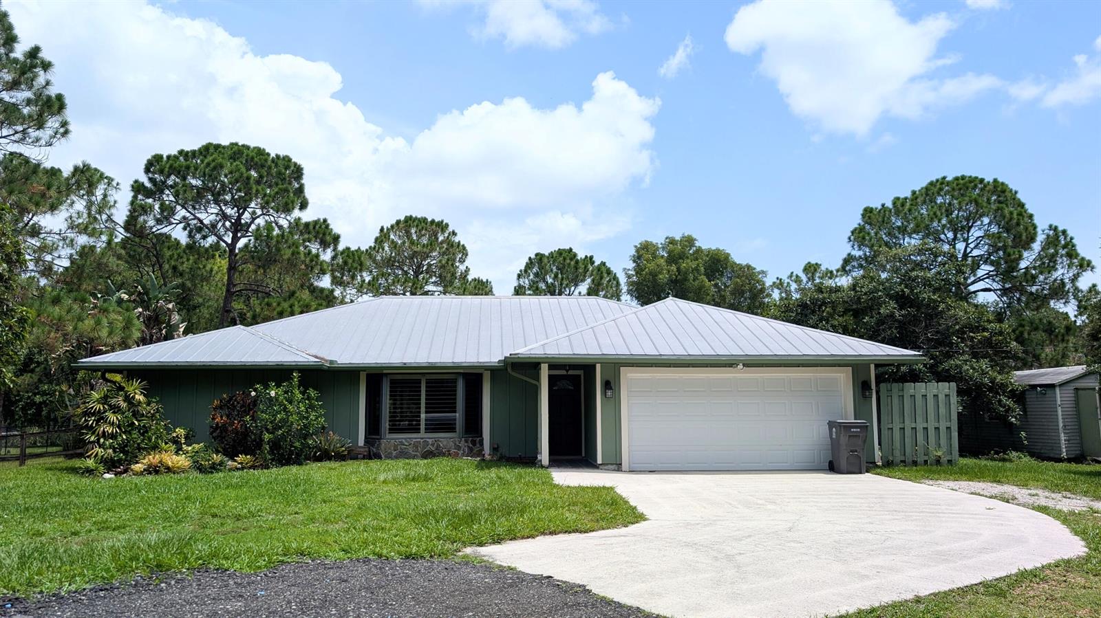 A single-story green house with a metal roof, a two-car garage, and a concrete driveway — 10173 150th Court N, Jupiter FL 33478, JUPITER, FL