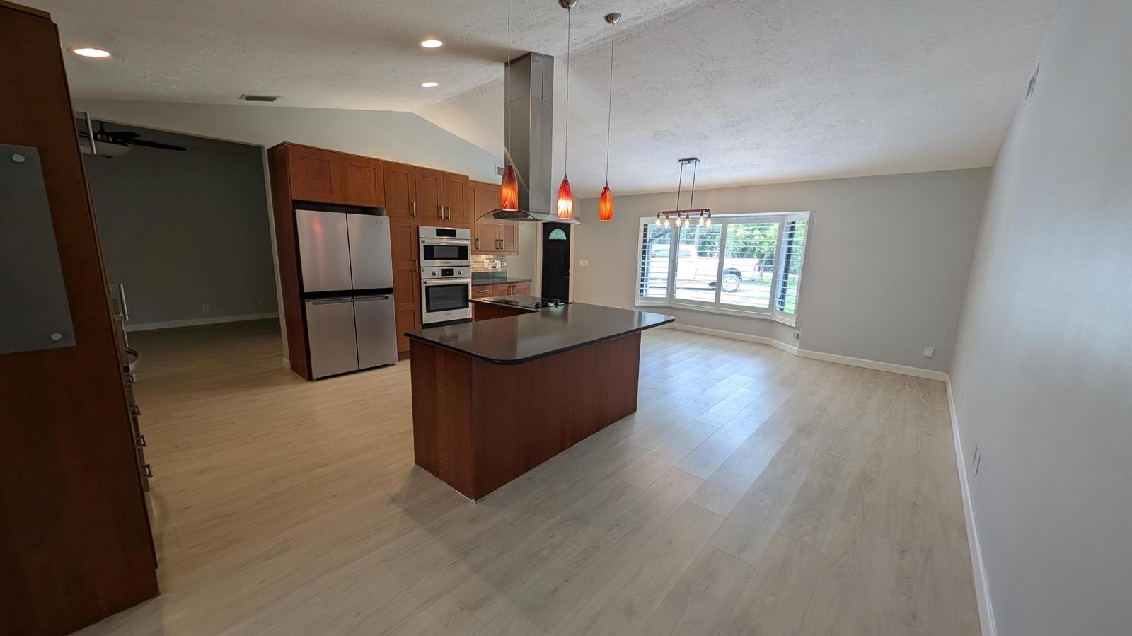A kitchen with wood cabinets, a central island, stainless steel appliances, and light wood flooring — 10173 150th Court N, Jupiter FL 33478, JUPITER, FL