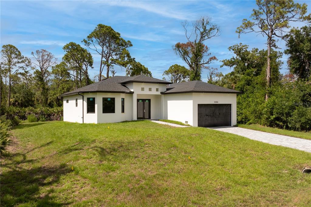 A modern, single-story white house with a dark roof and a two-car garage — 12086 CHAMBERLAIN BOULEVARD, PORT CHARLOTTE, FL