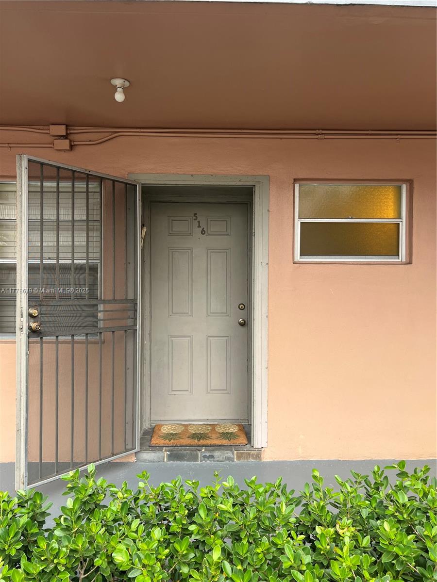 An exterior view of a residential unit entrance with a gray door and metal gate — 18555 NE 14th Ave # 516, Miami FL 33179, MIAMI, FL