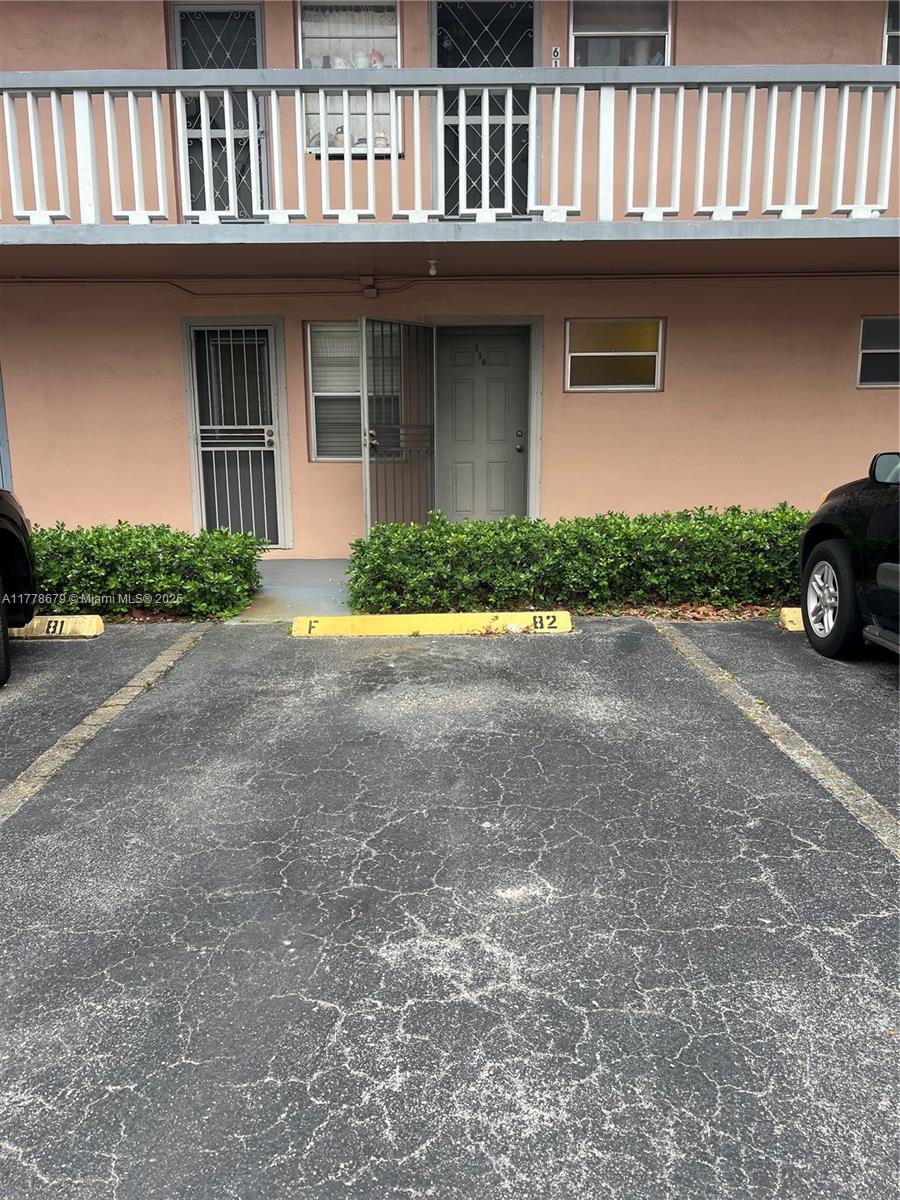 A two-story apartment building exterior features a ground-level entrance with a parking space marked 82 — 18555 NE 14th Ave # 516, Miami FL 33179, MIAMI, FL