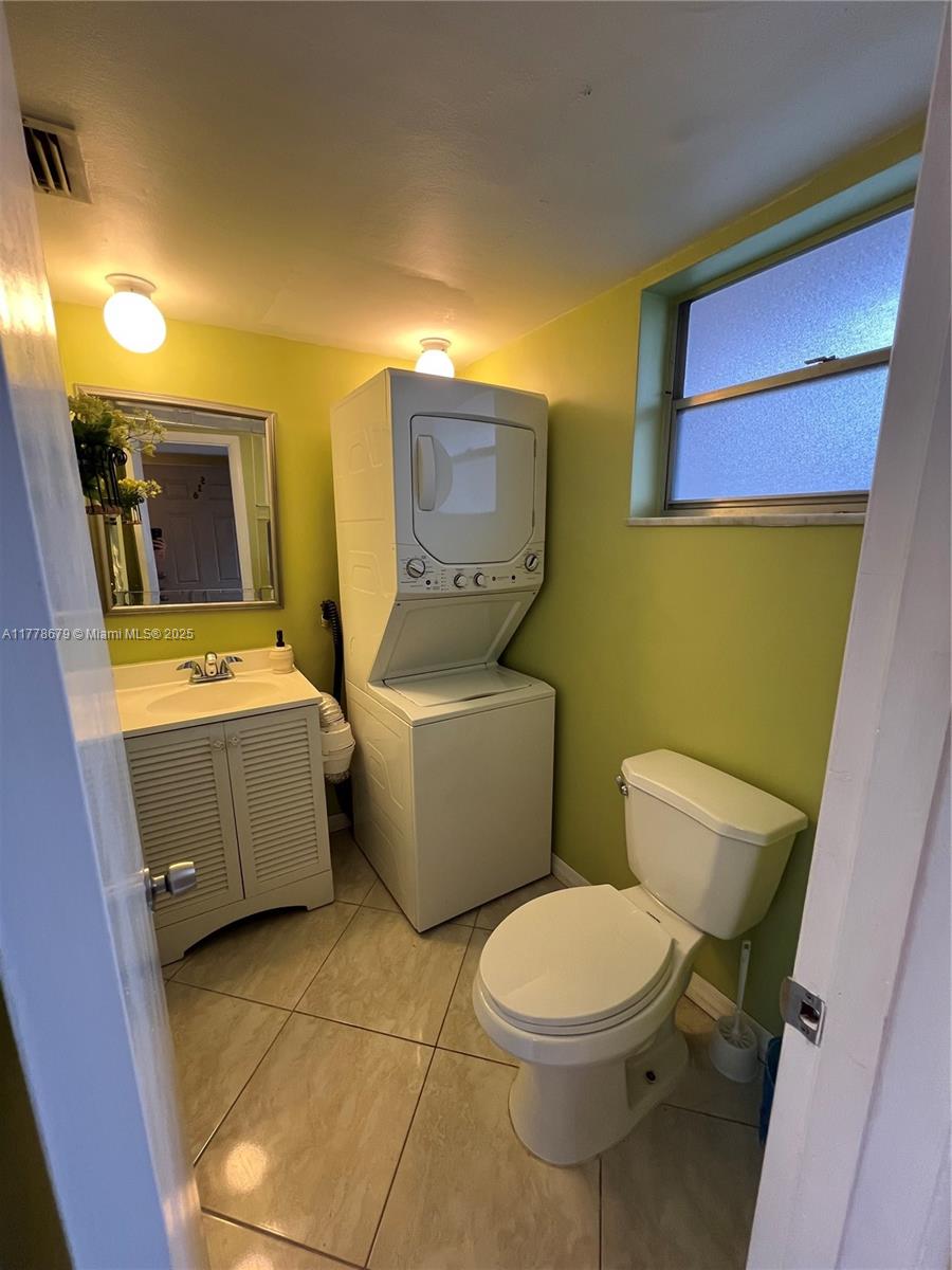 A small bathroom features a stacked washer-dryer unit, a vanity, and a toilet — 18555 NE 14th Ave # 516, Miami FL 33179, MIAMI, FL