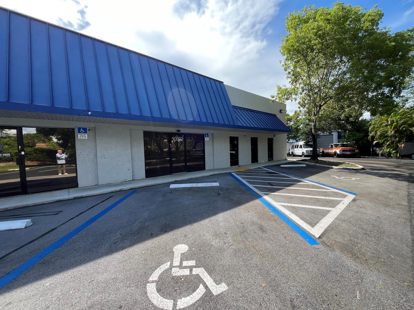Exterior view of a commercial building with a blue metal awning and accessible parking spaces — 10002 NW 46th Street # 10002, Sunrise FL 33351, SUNRISE, FL