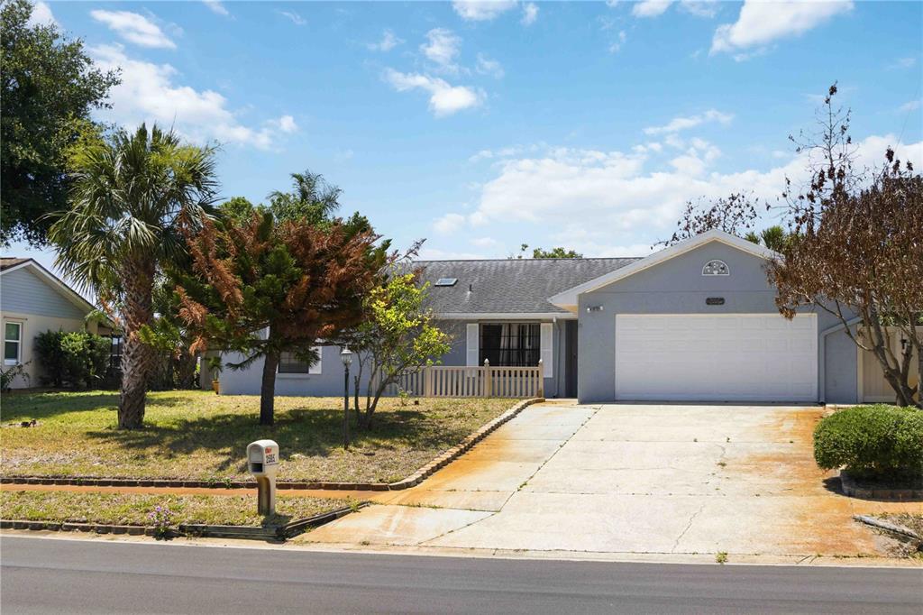 A single-story house with a gray exterior, a two-car garage, and a concrete driveway — 2595 WHITE OAK LANE, TITUSVILLE, FL