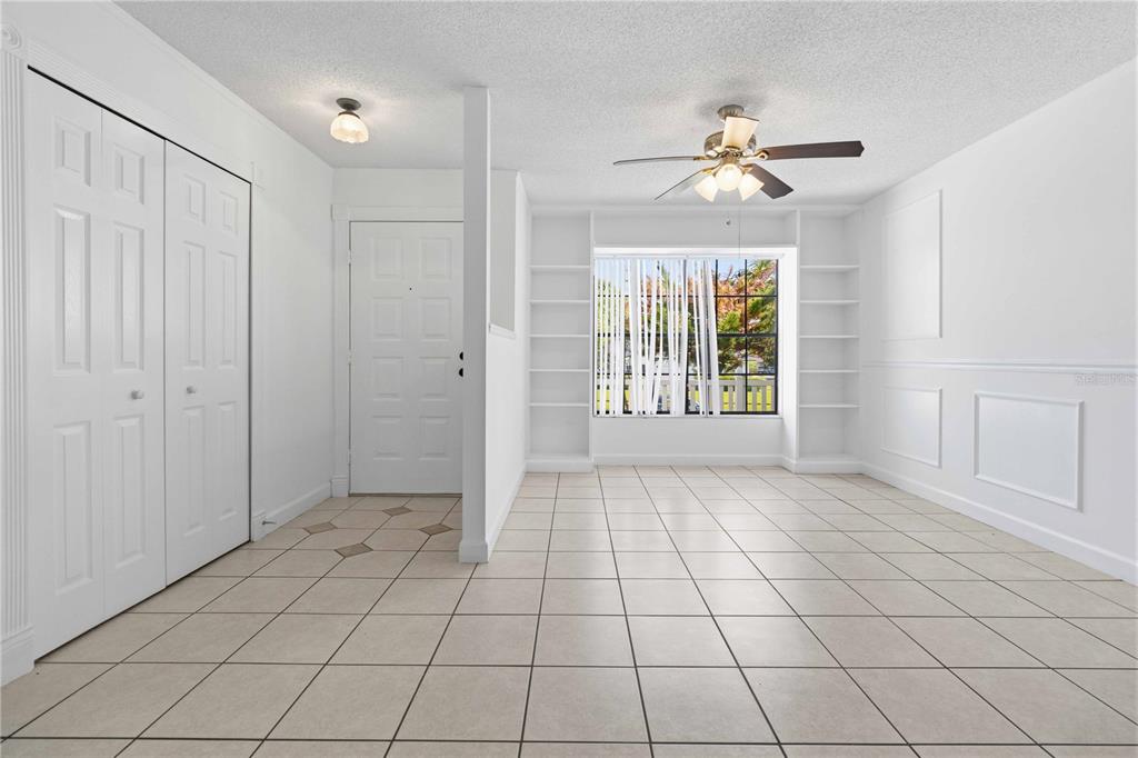 An empty room with white walls, tiled floors, built-in shelving, and a ceiling fan — 2595 WHITE OAK LANE, TITUSVILLE, FL