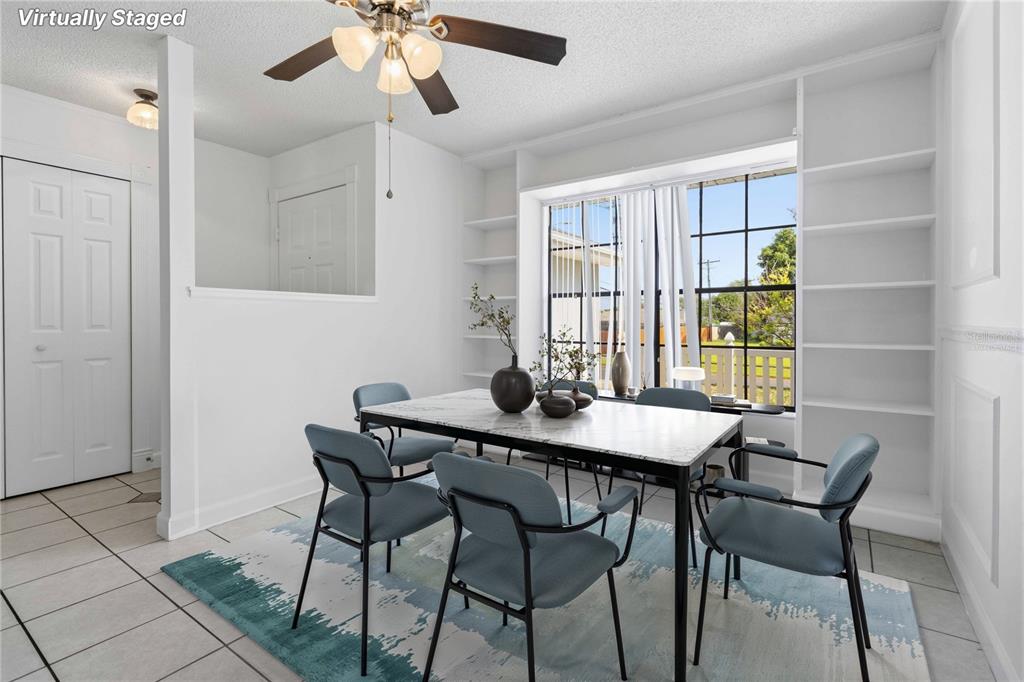 A dining room with a marble table, blue chairs, built-in shelves, and a large window — 2595 WHITE OAK LANE, TITUSVILLE, FL