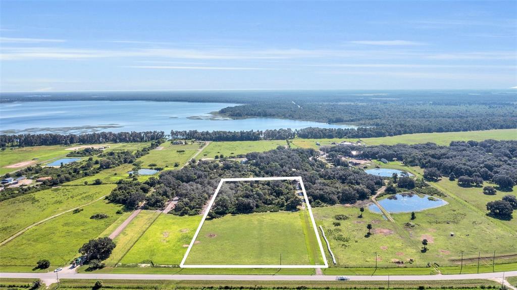 An aerial view shows a rectangular plot of land outlined in white near a lake — CANOE CREEK ROAD, ST CLOUD, FL