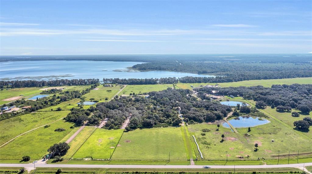 An aerial view shows a large rural property with green pastures, trees, and a lake — CANOE CREEK ROAD, ST CLOUD, FL