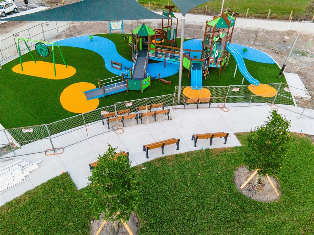 An aerial view shows a fenced playground with play structures, artificial turf, and park benches — 2001 SW FEARS AVENUE, PORT ST LUCIE, FL