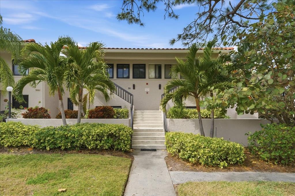 A two-story building exterior features a central staircase leading to an elevated entrance — 1802 MARINER DRIVE UNIT 30, TARPON SPRINGS, FL