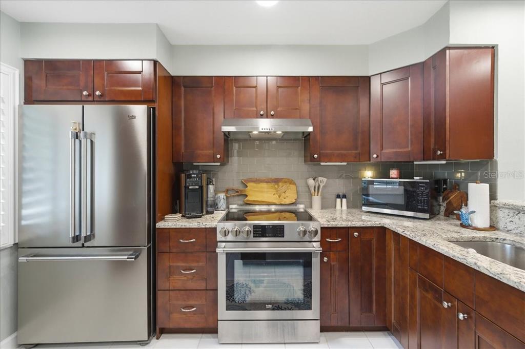 A kitchen features dark wood cabinets, stainless steel appliances, and granite countertops — 1802 MARINER DRIVE UNIT 30, TARPON SPRINGS, FL