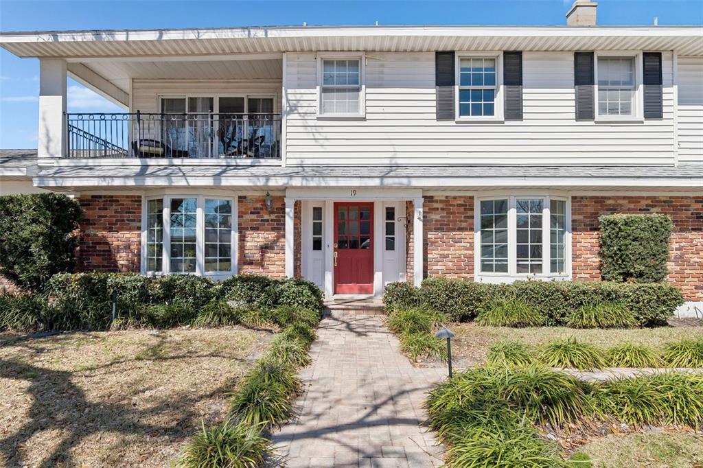 A two-story house features a red front door, brick lower level, and upper balcony — 19 SANDPIPER ROAD, TAMPA, FL