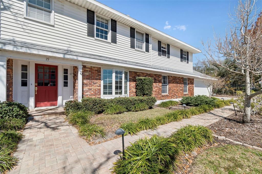 A two-story house with white siding, a brick facade, and a red front door — 19 SANDPIPER ROAD, TAMPA, FL