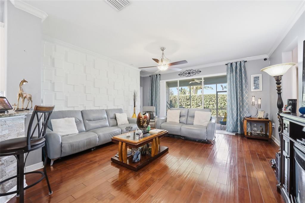 A living room features gray leather sofas, a textured white accent wall, and hardwood floors — 4020 CARTERET DRIVE, WINTER HAVEN, FL