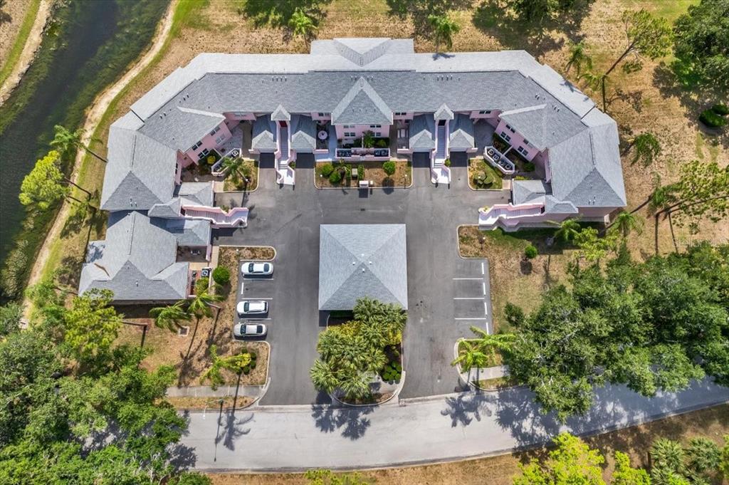 An aerial view of a U-shaped apartment building with a central parking area and pond — 4220 PINEBROOK CIRCLE UNIT 11, BRADENTON, FL