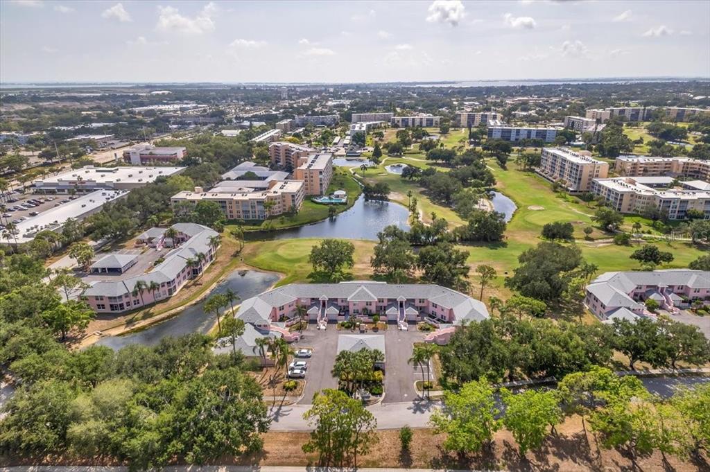 An aerial view of a pink apartment complex surrounded by a golf course and ponds — 4220 PINEBROOK CIRCLE UNIT 11, BRADENTON, FL