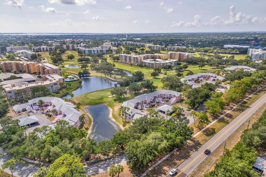 An aerial view of a residential complex with multi-story buildings, ponds, and a golf course — 4220 PINEBROOK CIRCLE UNIT 11, BRADENTON, FL