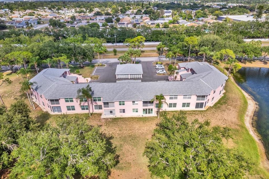 An aerial view of a U-shaped, pink multi-story apartment building next to a pond — 4220 PINEBROOK CIRCLE UNIT 11, BRADENTON, FL