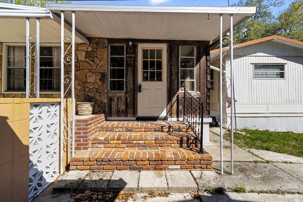 A brick staircase leads to the front door of a home with stone siding — 8109 E TIERRA COURT, INVERNESS, FL
