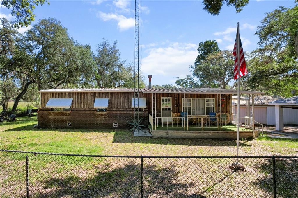 A single-story house with wood siding, brick base, a front porch, and a tall antenna — 8109 E TIERRA COURT, INVERNESS, FL