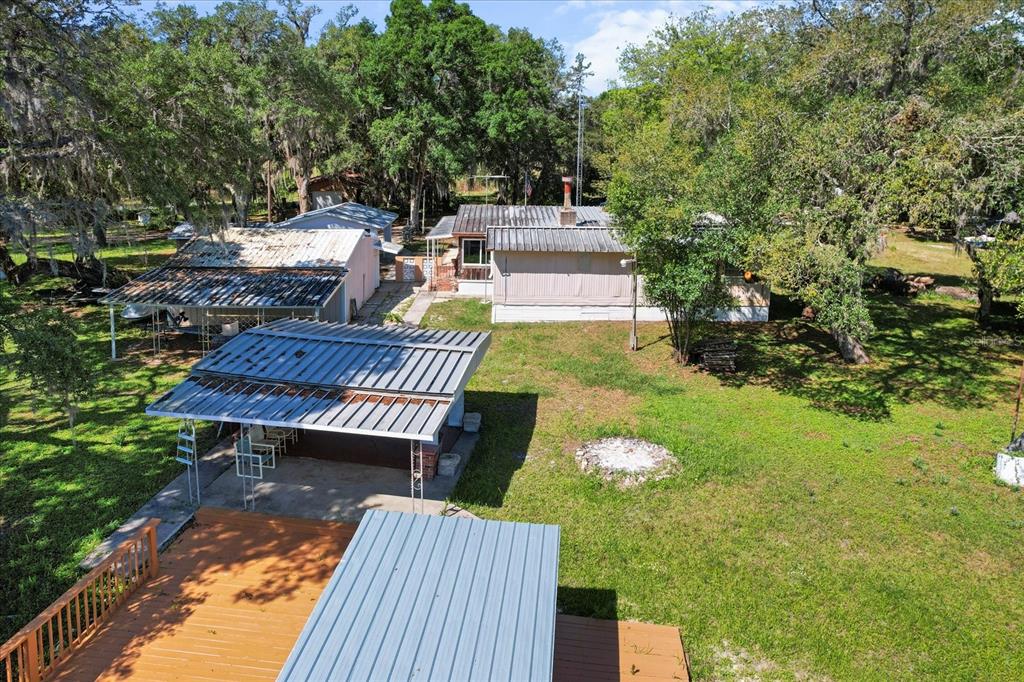 An aerial view of a property featuring a house, a detached carport, and a wooden deck — 8109 E TIERRA COURT, INVERNESS, FL