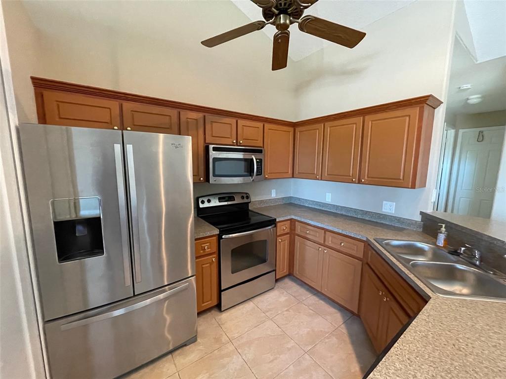 A kitchen features stainless steel appliances, wood cabinets, and a double-basin sink — 10365 PENDLETON AVENUE, ENGLEWOOD, FL
