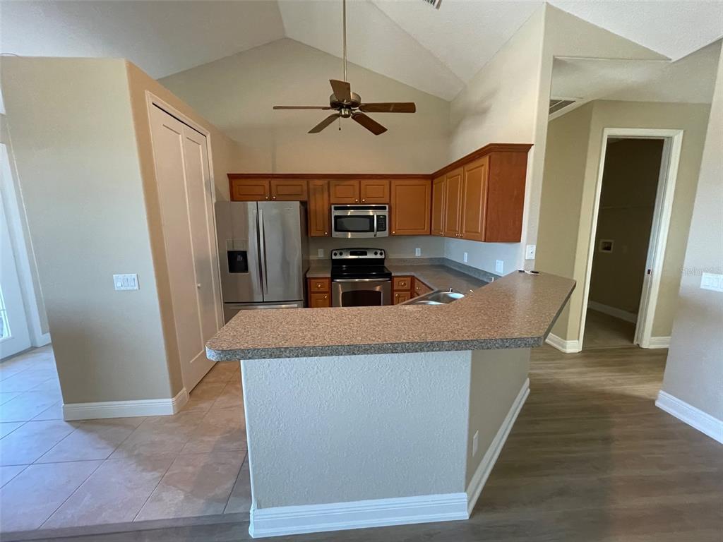 A kitchen with wood cabinets, stainless steel appliances, and a peninsula counter under a ceiling fan — 10365 PENDLETON AVENUE, ENGLEWOOD, FL