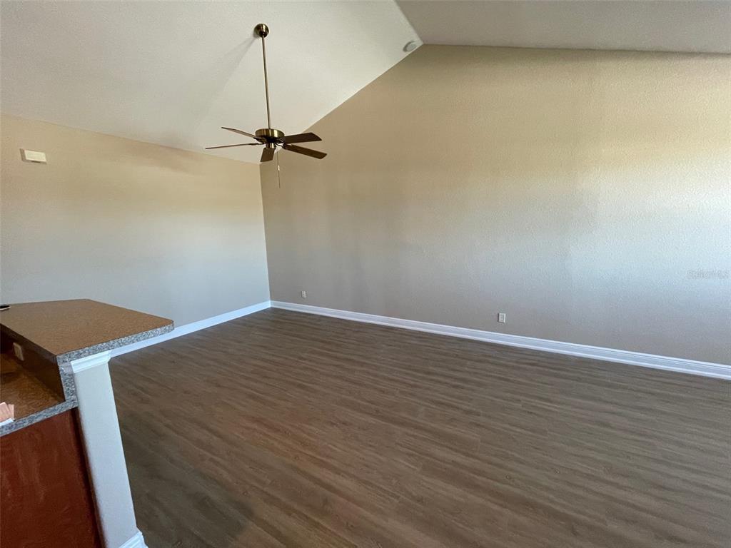 An empty room with vaulted ceilings, a ceiling fan, and wood-look flooring — 10365 PENDLETON AVENUE, ENGLEWOOD, FL