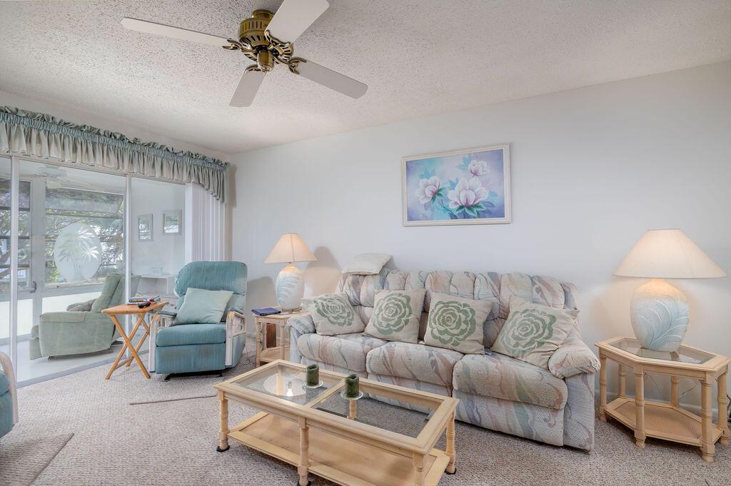 A living room features a patterned sofa, a blue recliner, a ceiling fan, and glass tables — 2929 SE Ocean Boulevard # 8, Stuart FL 34996, STUART, FL