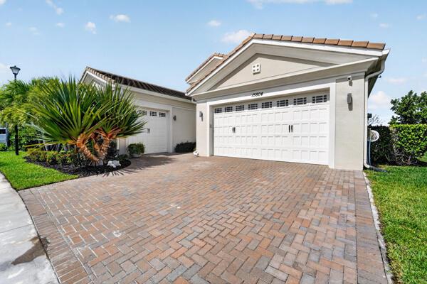 A beige house with a two-car garage and a brick paver driveway — 15804 Goldfinch Circle, Westlake FL 33470, WESTLAKE, FL