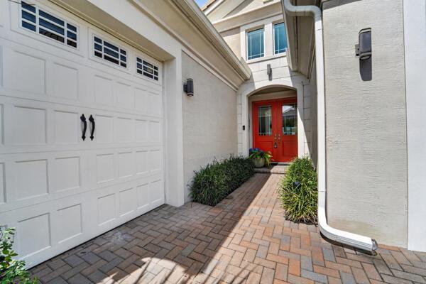 A brick walkway leads to a red front door beside a white garage door — 15804 Goldfinch Circle, Westlake FL 33470, WESTLAKE, FL