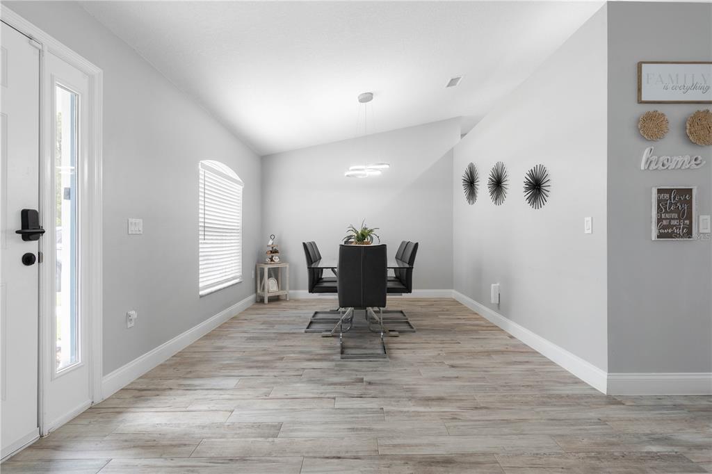 A dining room with light wood-look flooring, gray walls, and a modern black dining set — 64 BOSTON LANE, PALM COAST, FL