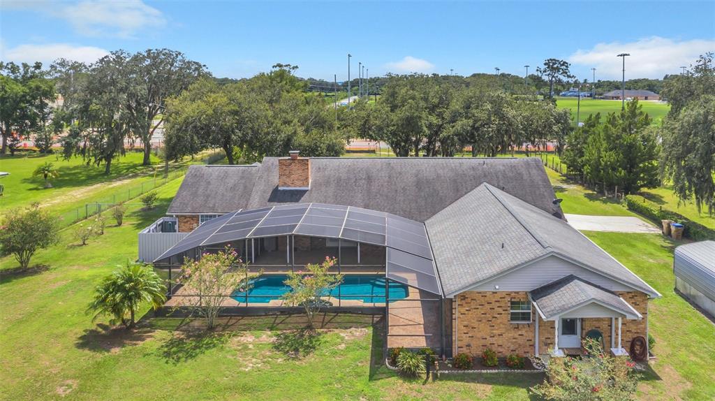 An aerial view of a brick house with a screened-in pool and a large yard — 4147 BOGGY CREEK ROAD, KISSIMMEE, FL