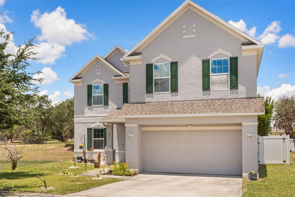A two-story house with light gray stucco, green shutters, and an attached two-car garage — 841 JEFFERSON BOULEVARD, HAINES CITY, FL