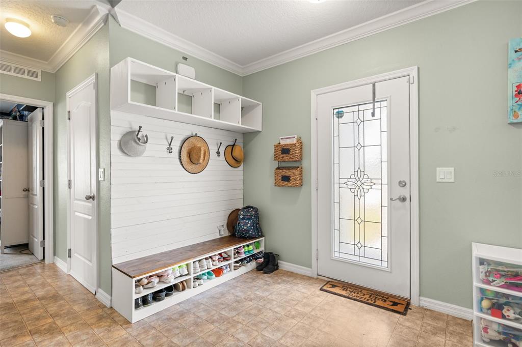 An entryway features a white mudroom bench with storage cubbies, coat hooks, and tiled flooring — 841 JEFFERSON BOULEVARD, HAINES CITY, FL
