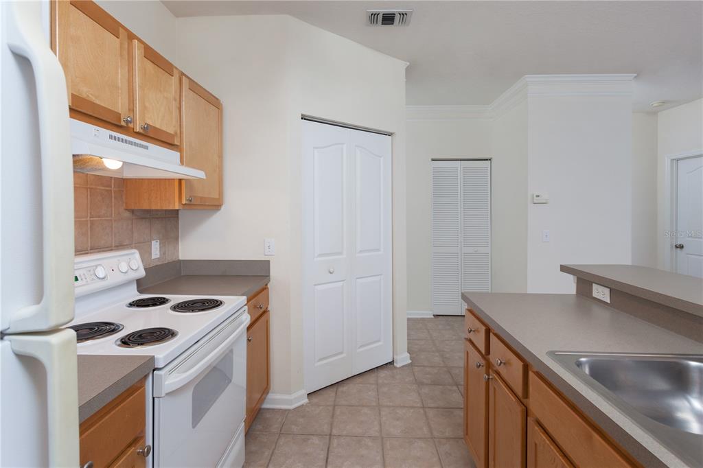 A kitchen features light wood cabinets, white appliances, a tiled floor, and a breakfast bar — 4207 S DALE MABRY HIGHWAY UNIT 10308, TAMPA, FL
