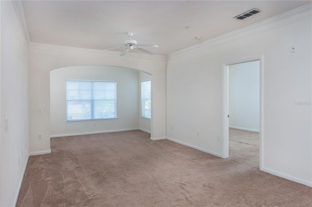 An empty room with beige carpet, white walls, an arched entryway, and a ceiling fan — 4207 S DALE MABRY HIGHWAY UNIT 10308, TAMPA, FL