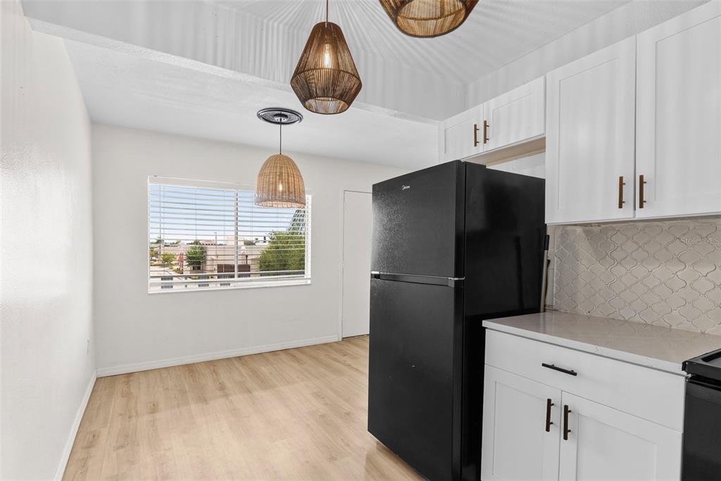 A kitchen with white cabinets, a black refrigerator, and a dining area with pendant lights — 11251 80TH AVENUE UNIT 307, SEMINOLE, FL