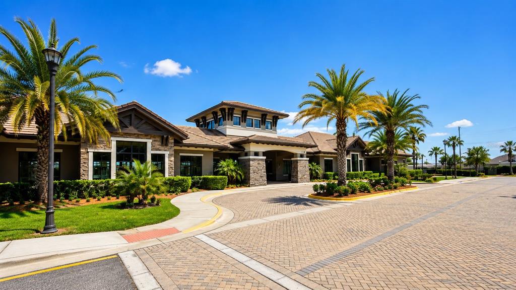 A tan single-story house with a two-car garage, a palm tree, and a paved driveway — 2608 NOUVEAU WAY, KISSIMMEE, FL