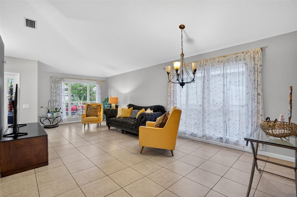 A living room features light tile floors, gray walls, a dark sofa, and yellow chairs — 11519 MISTY ISLE LANE, RIVERVIEW, FL