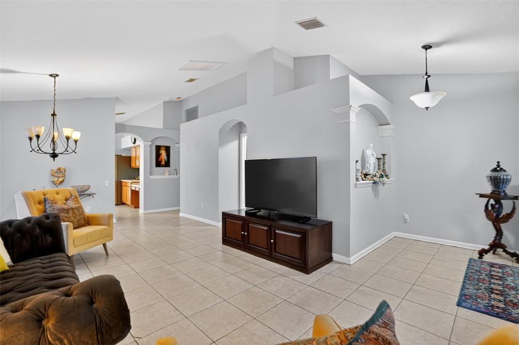 A living room with tile floors, a dark wood media console, and a central wall — 11519 MISTY ISLE LANE, RIVERVIEW, FL