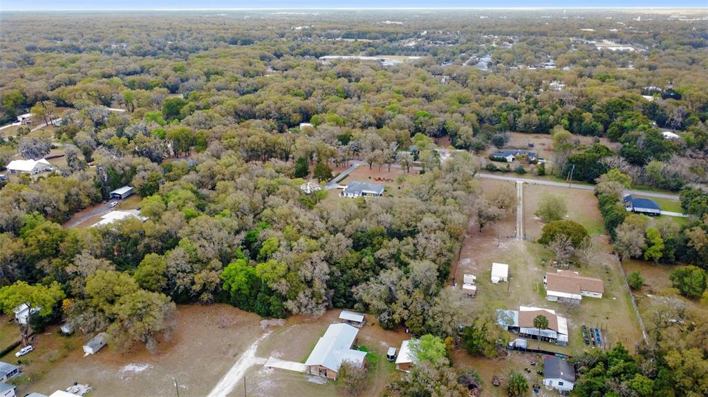 An aerial view shows several houses surrounded by dense trees and open grassy lots — N RIDGEWOOD AVENUE, DELAND, FL