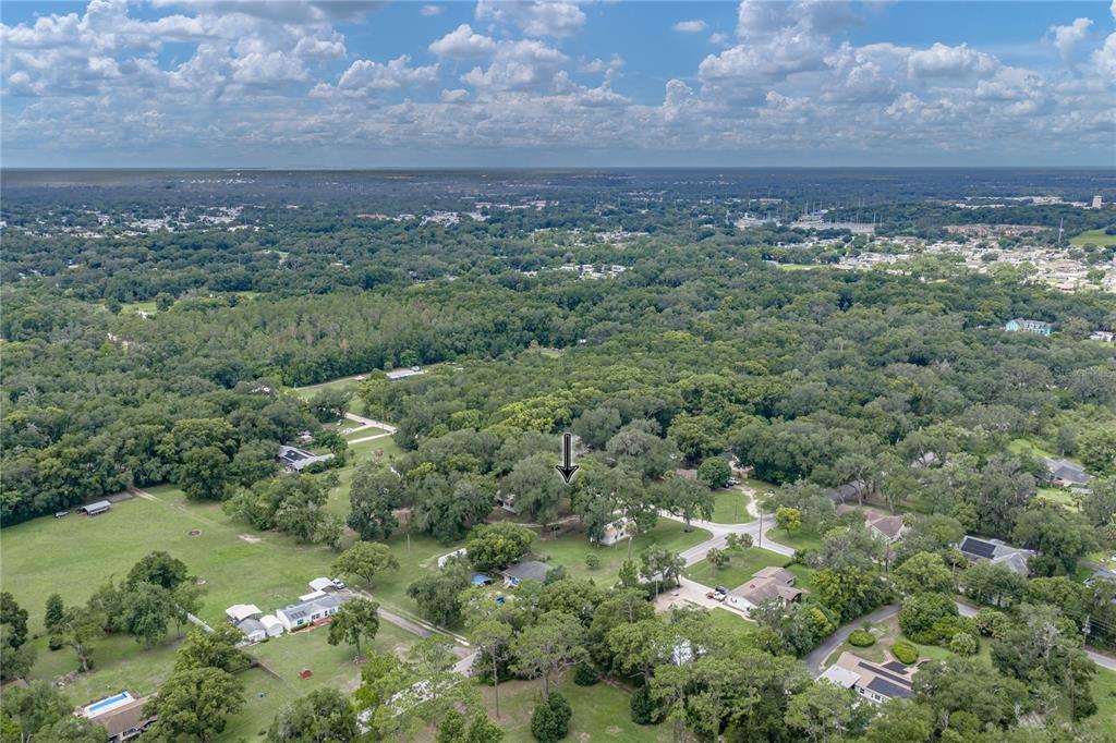 An aerial view shows a residential property surrounded by dense trees and green lawns — 7450 23RD STREET, ZEPHYRHILLS, FL