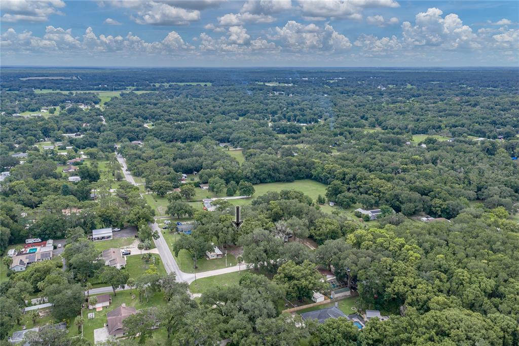 An aerial view shows a residential property surrounded by dense trees and a rural landscape — 7450 23RD STREET, ZEPHYRHILLS, FL